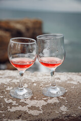 Two glasses of pink champagne on the handicap of the mountains and the sea. Travel and romance. Beautiful landscape. recreation and alcoholic beverages.