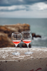 Two glasses of pink champagne on the handicap of the mountains and the sea. Travel and romance. Beautiful landscape. recreation and alcoholic beverages.