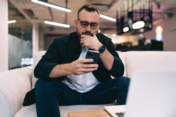 Thoughtful man using smartphone in office