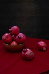 Fototapeta na wymiar Ripe red pomegranates on a table with a red cloth