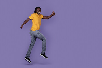 Excited african guy running in the air, showing thumb up