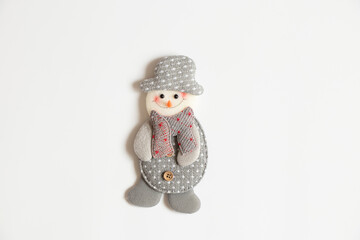 A homemade snowman made of gray fabric lies on a white background, a Christmas decoration