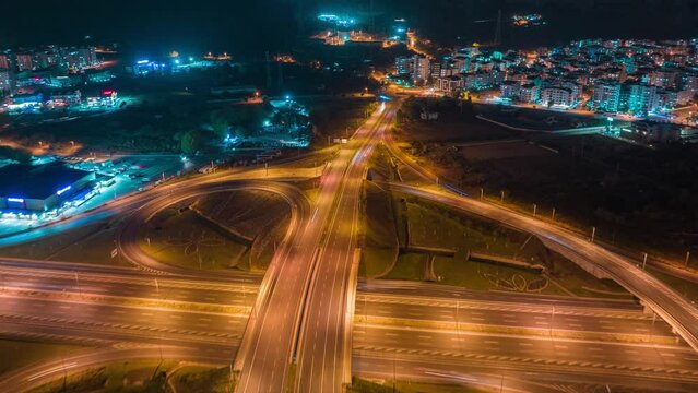 Aerial view of a multi-level stack interchange. Blue yellow neon light. Street lighting. Fast moving cars. Timelapse