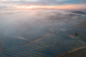 Atardecer con niebla sobre campo de paneles solares, energía renovable fotovoltáica 