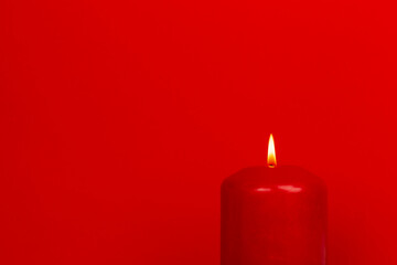 Red burning candle on simple red background - mockup for wishes
