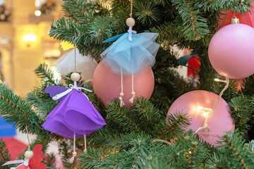 Angel dolls in multi-colored outfits on the Christmas tree.