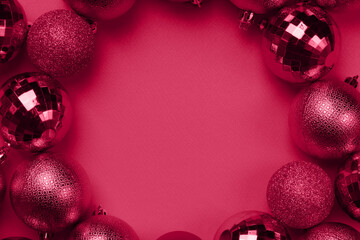 Circle frame of viva magenta Christmas bauble balls decorations on carmine red background with copy...