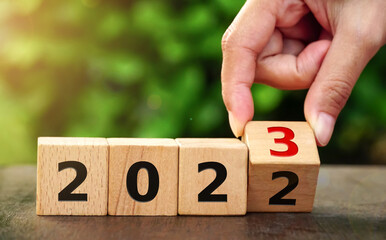 happy new year concept, Flipping of wooden cube block change from 2022 to 2023 on natural...
