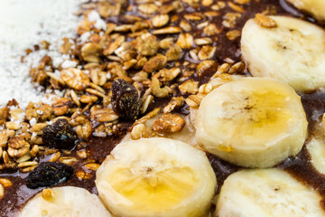 Brazilian açai in a white bowl with banana, powdered milk, honey, granola and walnut. Cashew nuts and Pará. Grey background. Selective focus