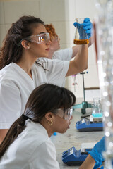 Group of young female chemistry scientists doing experiments in lab.	