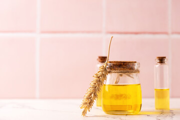 Natural skin care products. Bottles with organic wheat germ oil against pink tiled wall.   Beauty blogging, salon treatment concept. Selective focus. Place for text.. - 551616108