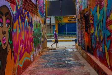 Obraz na płótnie Canvas Um homem passando ao final do corredor do Beco da Codorna - um ponto turístico da cidade de Goiânia.