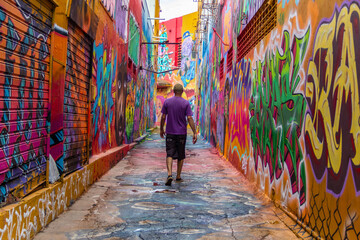 Obraz na płótnie Canvas Um homem, de costas, caminhando pelo corredor do Beco da Codorna, um lugar pitoresco na cidade de Goiânia. Ponto turístico.