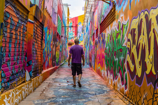 Um homem, de costas, caminhando pelo corredor do Beco da Codorna, um lugar pitoresco na cidade de Goi&acirc;nia. Ponto tur&iacute;stico.