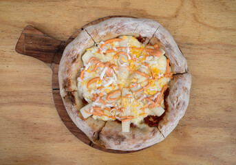 Top view of a gourmet pizza with tomato sauce, mozzarella cheese, palmettos, grated boiled egg and thousand island sauce on the wooden table.