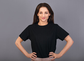 Happy toothy smiling woman posing in blank casual black t-shirt on grey studio background - 551617708