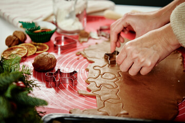Female hands cutting figures from ginger dough with cutter. Cooking gingerbread cookies to preparing for winter holidays. Christmas baking