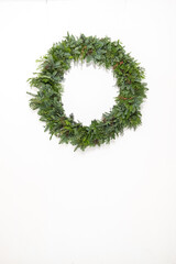 Christmas wreath of living branches of coniferous trees on a white background. DIY new year decor.