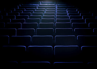 Fototapeta premium Empty movie theatre with blue light of the projector on the seats