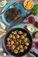 Dinner table with various snacks in the concept of homemade food, vegetables, herbs, fried steak in a pan, new potatoes