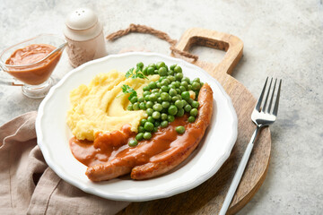 Bangers and mash. Grilled sausages with mash potato and green pea on white plate on grey background. Traditional dish of Great Britain and Ireland. BBQ beef sausages. Top view.