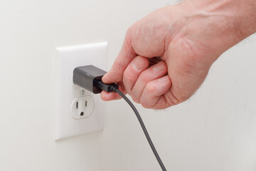 Person connecting usb adapter plug into electrical wall outlet