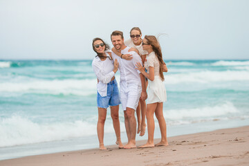 Family of young parent and two kids smiling and enjoy time together on the beach vacation