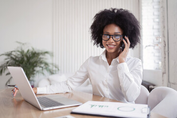 A happy woman makes a report online for free. Formal wear white shirt and business glasses for the computer.