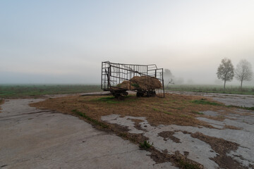 Kaputter Anh&auml;nger auf einem Feld im Nebel