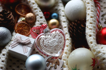 Various colorful Christmas ornaments, small presents and seasonal spices on white knitted blanket. Selective focus.