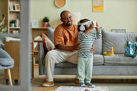 Full length portrait of cute black child wearing VR headset and enjoying virtual reality entertainment for children, copy space - Powered by Adobe