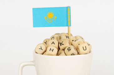 The flag of Kazakhstan sticks out of a cup with cubes on which letters are depicted.