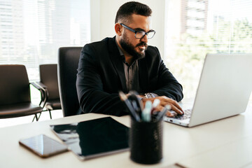 Young Brazilian businessman working on laptop in modern office