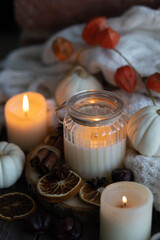 Fototapeta na wymiar Autumn home composition with aromatic candle, dry citrus, cinnamon, anise. Aromatherapy on a grey fall morning, atmosphere of cosiness and relax. Wooden background close up