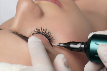 Young woman undergoing procedure of permanent eye makeup, closeup
