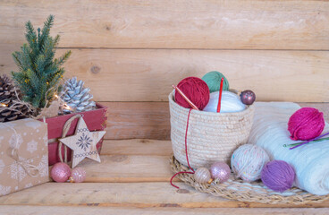 woolen colorful balls with crochet hooks in a wooden box, with christmas balls on wooden ground