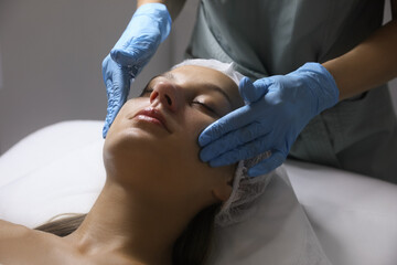 Obraz na płótnie Canvas Young woman receiving facial massage in salon