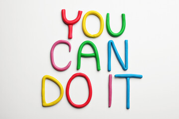 Motivational phrase You Can Do IT made of colorful plasticine on white background, flat lay