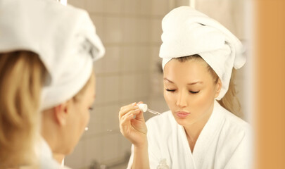 Woman looking in the mirror Applying the cream..Magic anti-aging cream