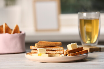 Tasty toasts with butter served on white wooden table