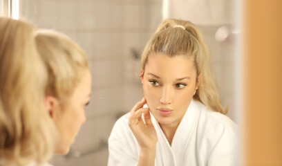 Obraz na płótnie Canvas Woman looking in the mirror Applying the cream..Magic anti-aging cream
