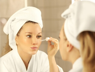 Woman looking in the mirror Applying the cream..Magic anti-aging cream