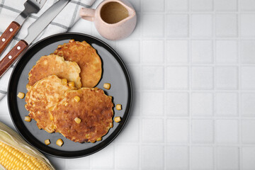 Tasty corn pancakes served on white tiled table, flat lay. Space for text