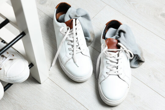 Sneakers With Dirty Socks On White Wooden Floor Indoors