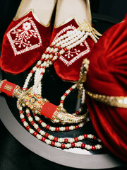Red shoes and Sehra for groom in a traditional Indian wedding ceremony and placed near coral string of beads