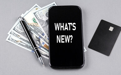 Credit card and text WHAT'S NEW on smartphone with dollars and pen. Business concept