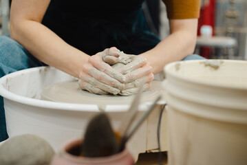 Closeup of potter hands working on pottery wheel in ceramic studio with clay hands front view with pottery wheel in motion