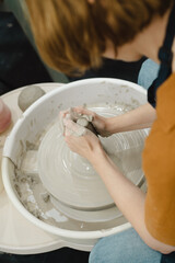 Closeup of potter hands working on pottery wheel in ceramic studio with clay hands side view with pottery wheel in motion