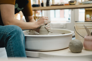 Closeup of potter hands working on pottery wheel in ceramic studio with clay hands side view with pottery wheel in motion