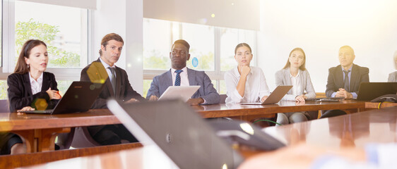Team of professional age-diverse multiethnic business people having discussion at table during corporate briefing in boardroom, planning new project strategy, brainstorming together